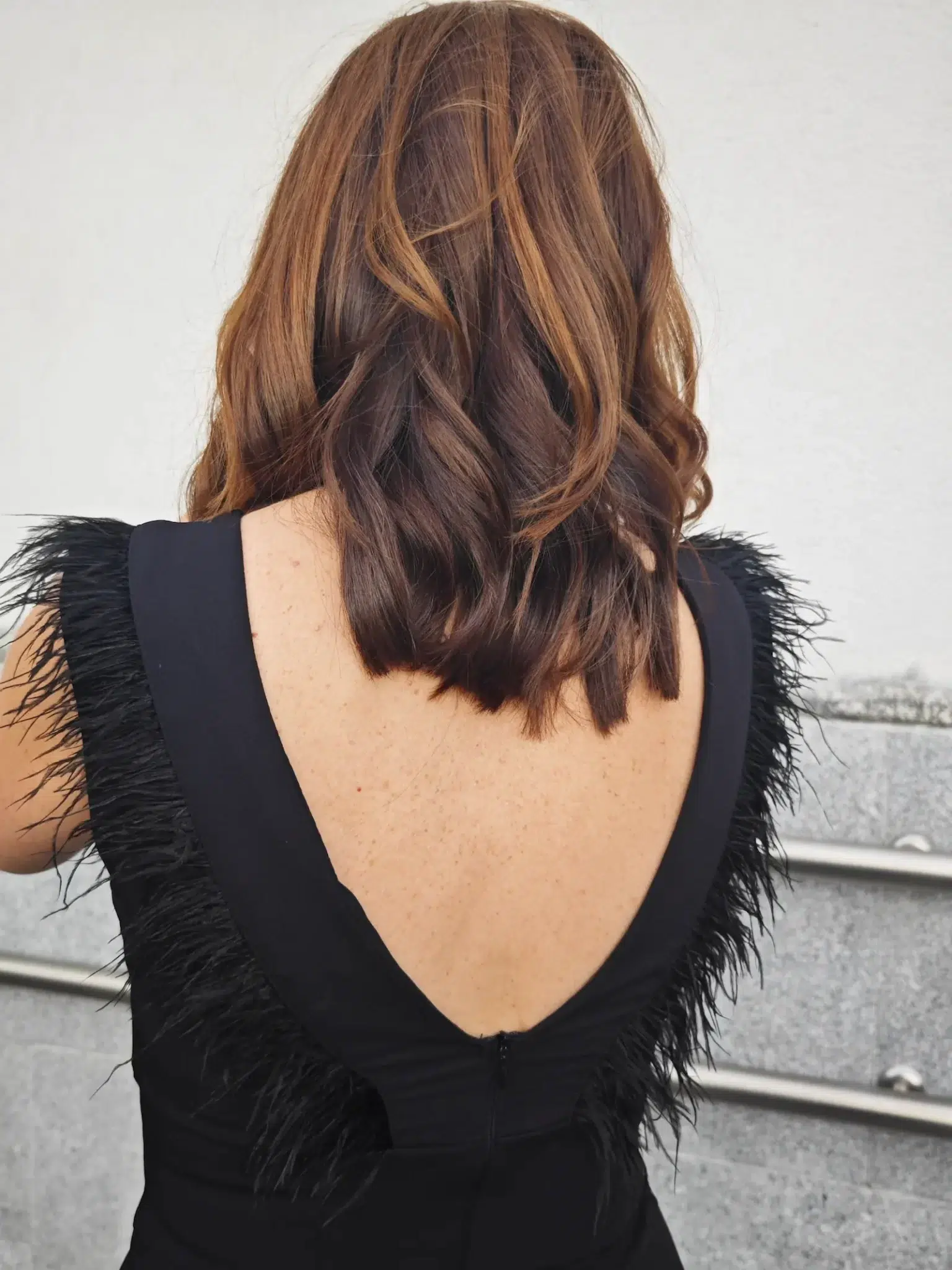 vestido midi negro con escote en pico y plumas en el escote